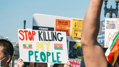 man in black polo shirt holding white and yellow signage during daytime