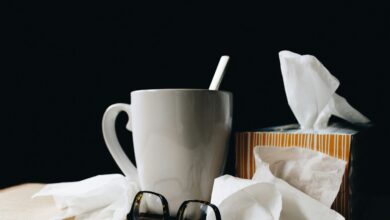 white ceramic mug on white table beside black eyeglasses